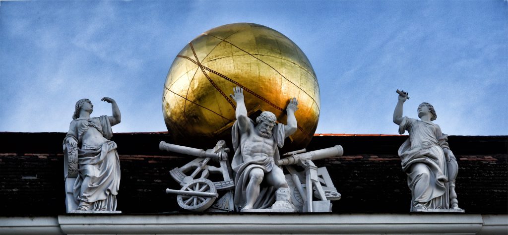 Don't do it all alone. Let me do the heavy lifting. A statue of Atlas supporting a golden world, representing the power of clear writing to carry the weight of a company's complex ideas.